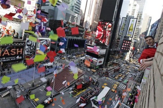 Times Square Alliance President Tim Tompkins throws a handful of confetti from eight stories above onto the streets of Times Square, Thursday, Dec. 29, 2011 in New York. The airworthiness test is in preparation for the release of one ton of confetti by hand from various buildings in Times Square at midnight on New Year’s Eve. (AP Photo/Mary Altaffer)